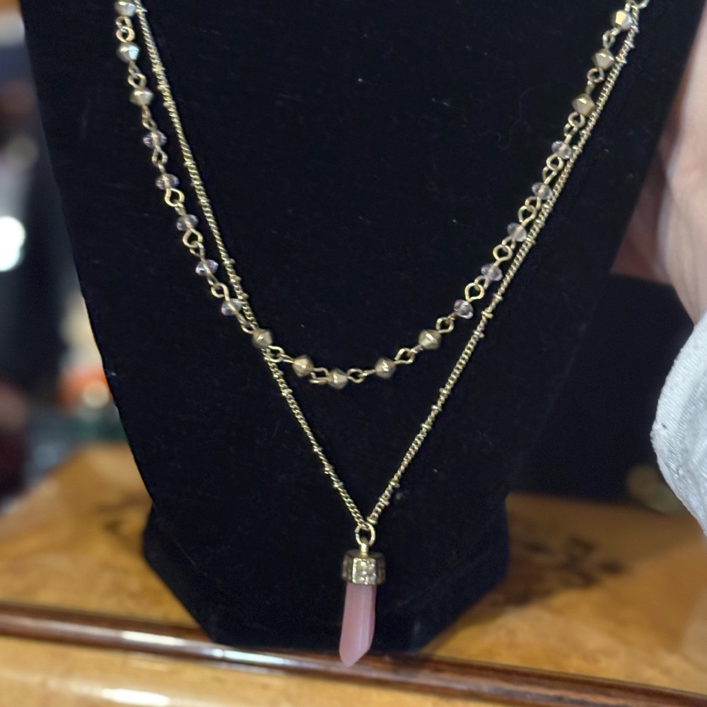 Two strand branded necklace in gold tone with a pink pendant.